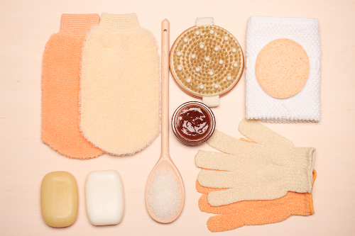 Gegenstände für Peeling der Haut: Peelinghandschuh, Seife und Scheuerbürste.